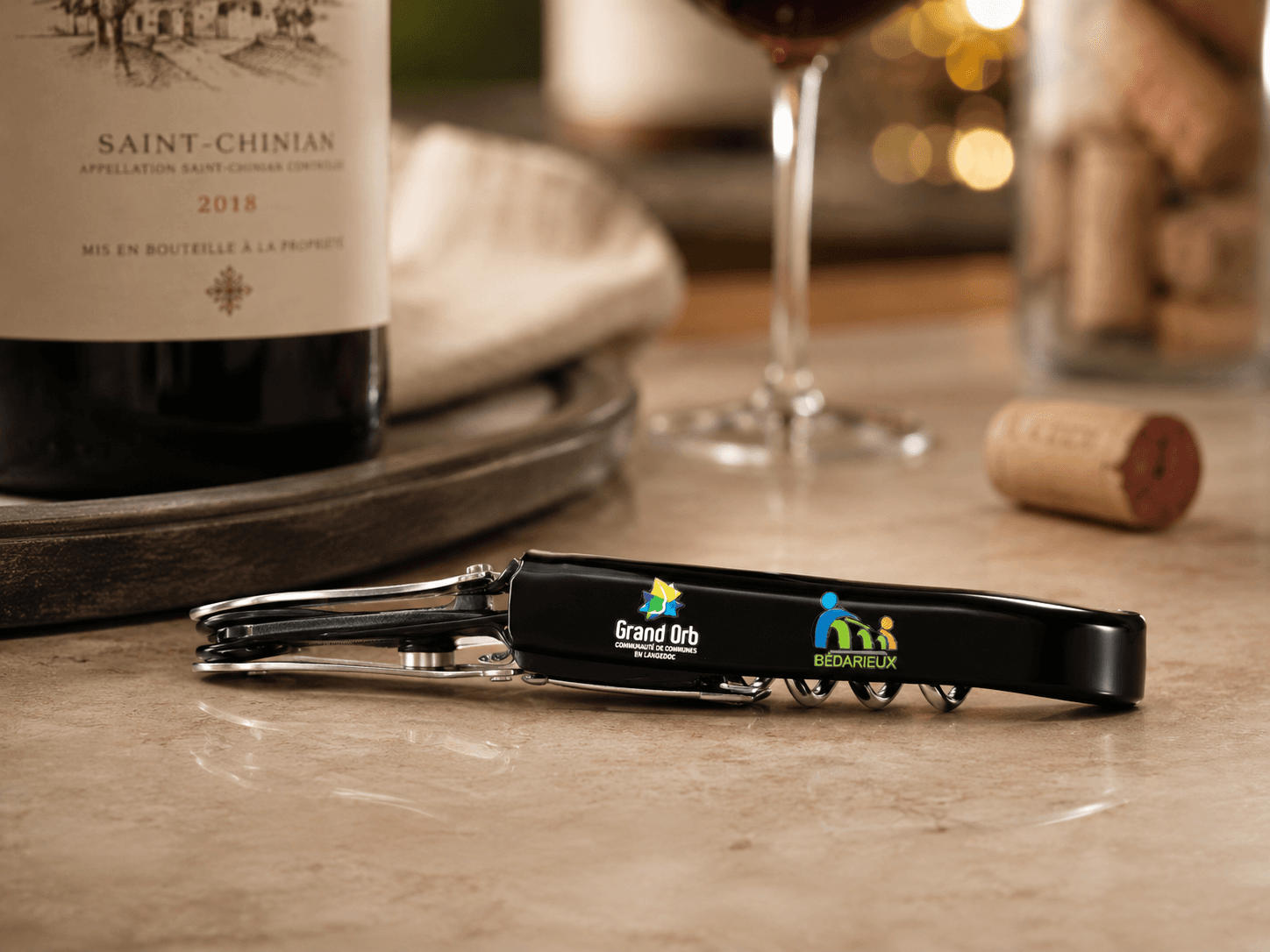Tire-bouchon personnalisé Grand Orb Bédarieux avec verres et bouteille de Saint-Chinian lors de la soirée œnologique