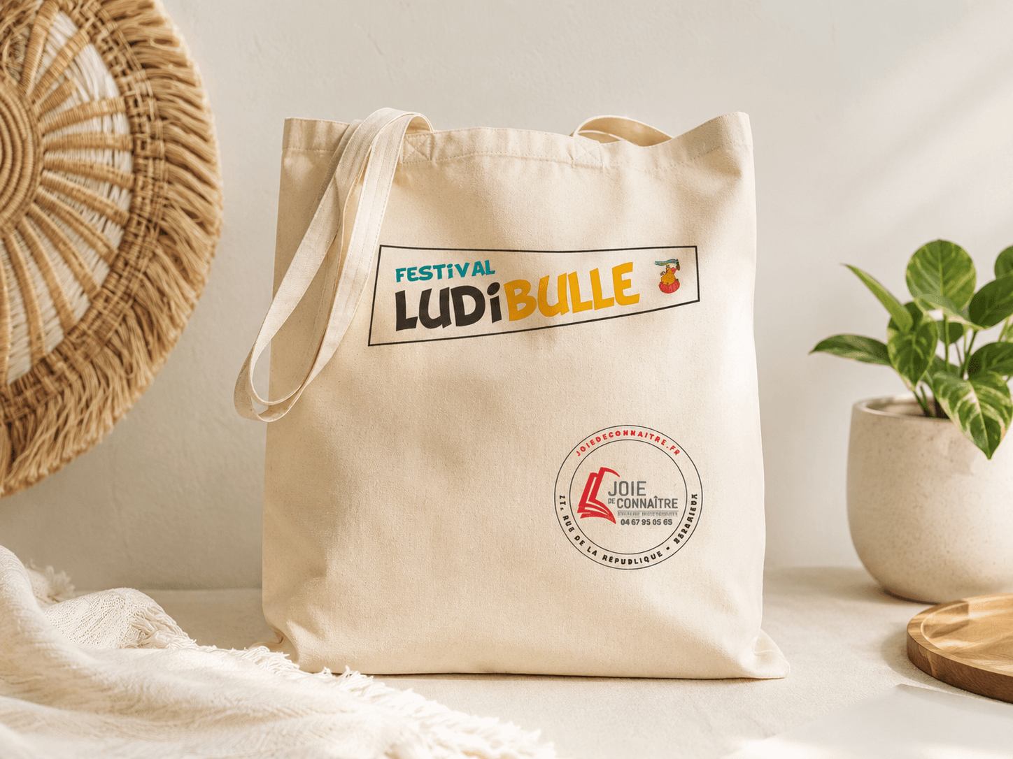 Piles de tote bags LudiBulle imprimés à l'atelier sous le panneau « Production locale, rapide & responsable »