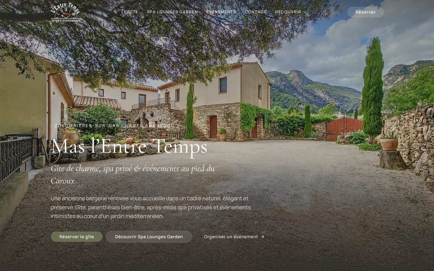 Accueil de mas-lentretemps.fr : la cour du Mas en pierre, le Caroux en fond, le titre Mas l'Entre Temps en italique et les boutons pour réserver le gîte, découvrir le spa ou organiser un événement